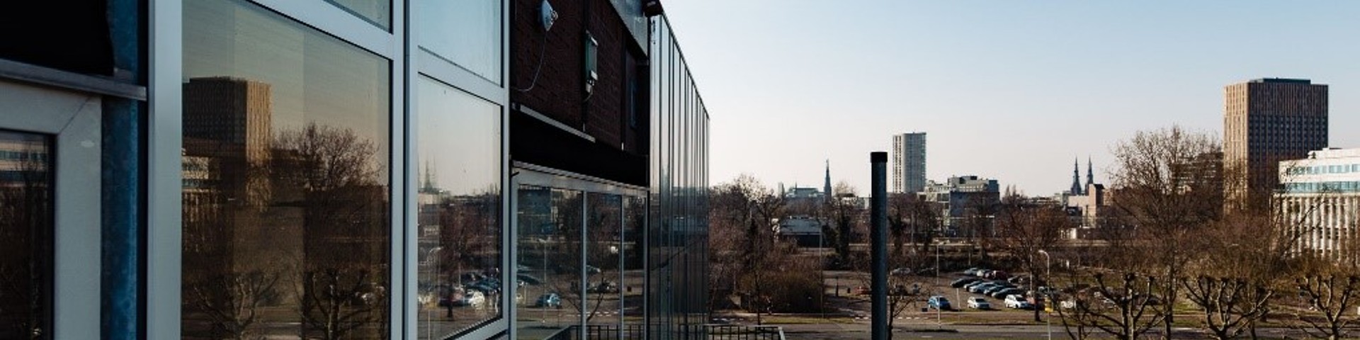 Close up of a glass building with many windows with the city in the background