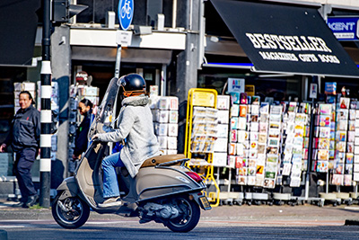 Snorfietsen met verbrandingsmotor in een straat voor een winkel genaamd Bestseller met kaarten