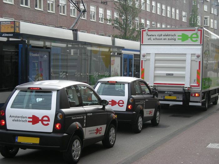 Elektrische auto's en een elektrische vrachtwagen rijden door Asmterdam