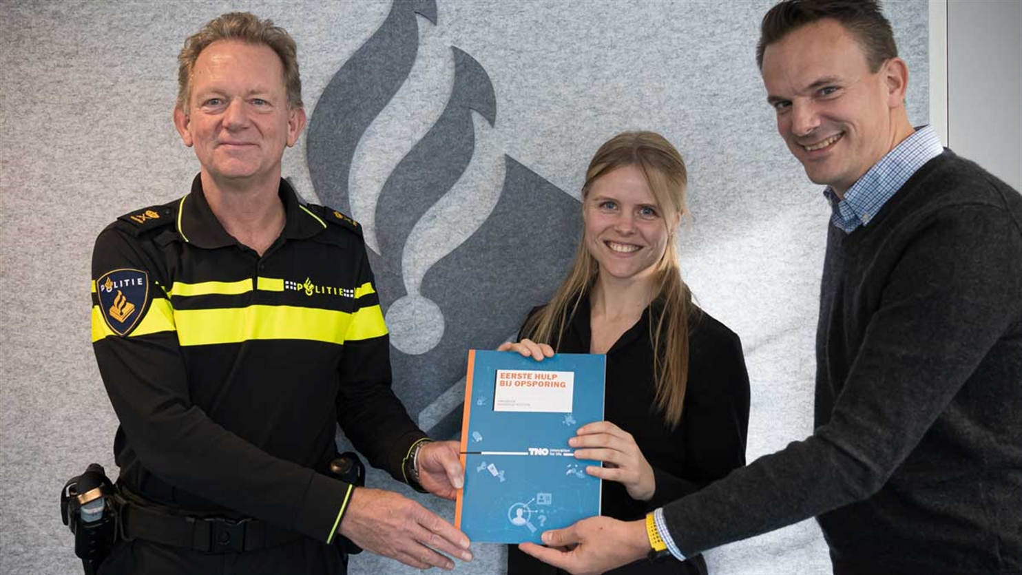 Policeman receiving the handbook for help with detection by TNO