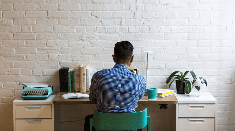 man die aan zijn bureau op zijn laptop aan het werken is
